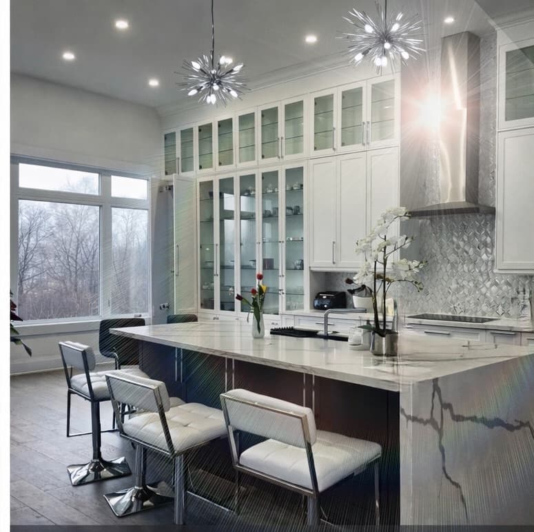 Modern white kitchen featuring a marble island, glass-front cabinets, and starburst pendant lights.